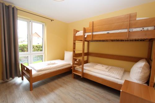 two bunk beds in a room with a window at Haus Sterntaucher Appartement 4 in Thiessow