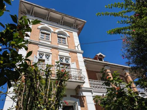 a tall brick building with white windows and a balcony at Le Manoir in Antananarivo