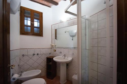 a bathroom with a sink and a toilet and a mirror at Tenuta Decimo - Il Borgo Di Mariano in San Gimignano