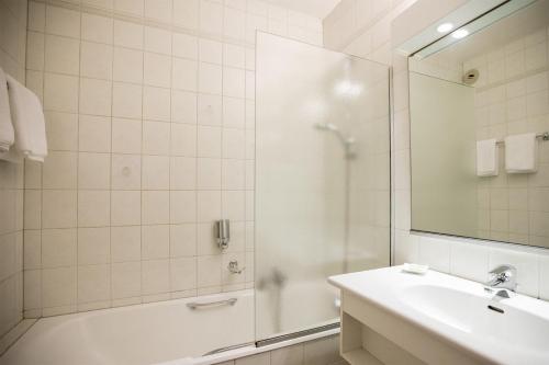 a bathroom with a tub and a sink and a shower at Auberge du Cheval Blanc depuis 1785 in Westhalten
