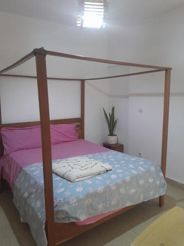 1 dormitorio con cama de madera y dosel en Pied a terre in Ouakam, en Ouakam