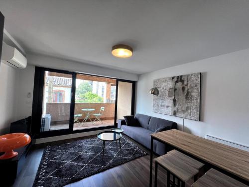 ein Wohnzimmer mit einem Sofa und einem Tisch in der Unterkunft Sublime T2 avec balcon in Montauban