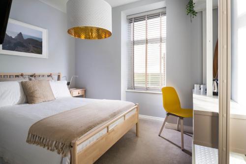 a bedroom with a bed and a yellow chair at Housel Bay Hotel in Lizard