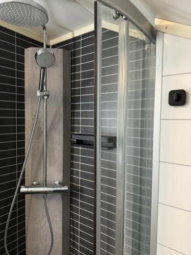 a shower in a bathroom with black tiles at Heggelund in Svensby