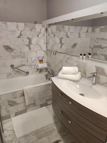 une salle de bain avec un lavabo, un miroir et une baignoire dans l'établissement L'Escale - Appartement vue mer, à Concarneau