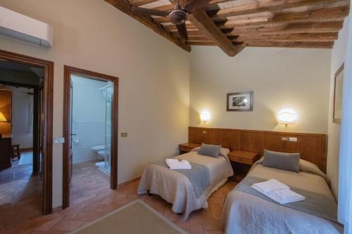 two beds in a room with a bathroom at Tenuta Decimo - Il Borgo Di Mariano in San Gimignano