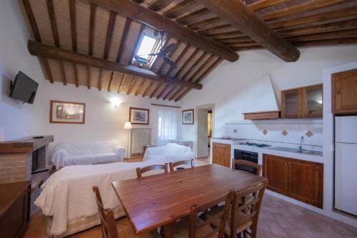 a kitchen and living room with a wooden table and a dining room at Tenuta Decimo - Il Borgo Di Mariano in San Gimignano
