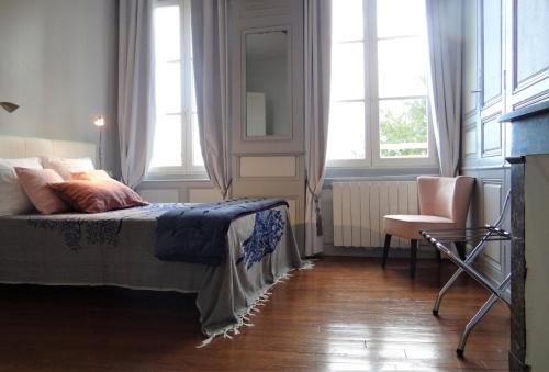 um quarto com uma cama, uma cadeira e janelas em Le Cardinal em Chartres