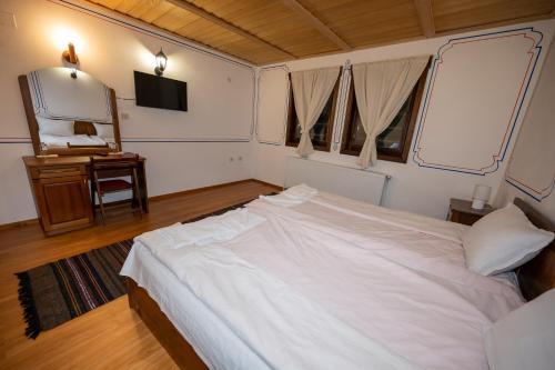 a bedroom with a white bed and a mirror at Недкова къща in Koprivshtitsa
