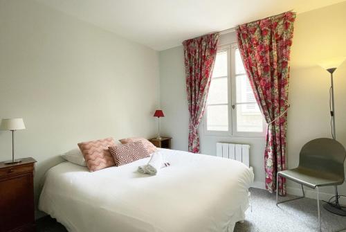 ein Schlafzimmer mit einem Bett, einem Fenster und einem Stuhl in der Unterkunft Le Cloître pour 4 personnes in Chartres
