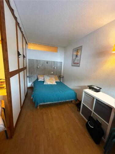 - une chambre avec un lit bleu et un bureau dans l'établissement Puy St Vincent 1800 au pied des pistes, à Puy-Saint-Vincent