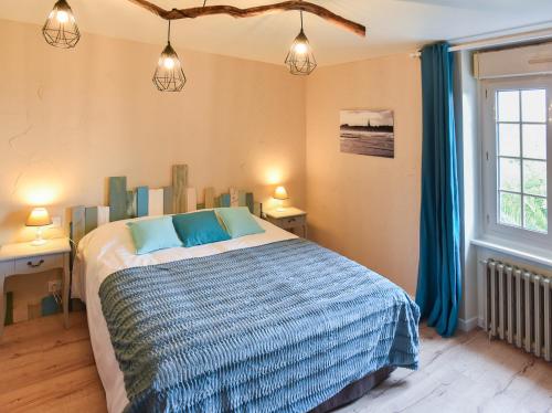a bedroom with a bed with blue pillows and a window at Petite Emeraude in Cancale