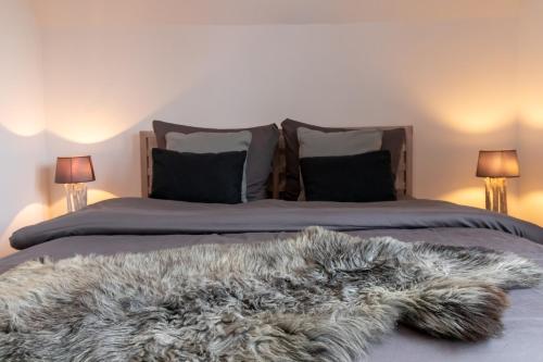 a bed with a furry blanket on it with two lamps at Dat Huuske - das besondere Ferienhaus in Salzhausen