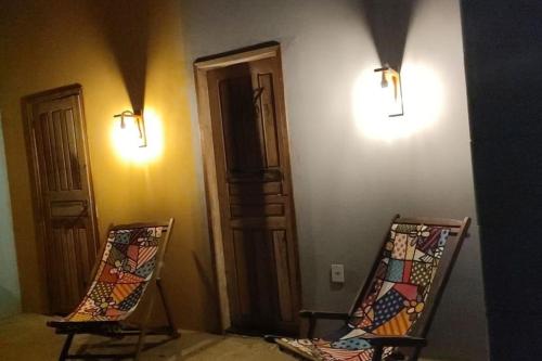2 Stühle in einem Zimmer mit Lampen an der Wand in der Unterkunft Chácara Refúgio de Assis in Pirambu