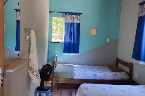 2 Betten in einem Zimmer mit blauen Wänden und einem Fenster in der Unterkunft Chácara Refúgio de Assis in Pirambu