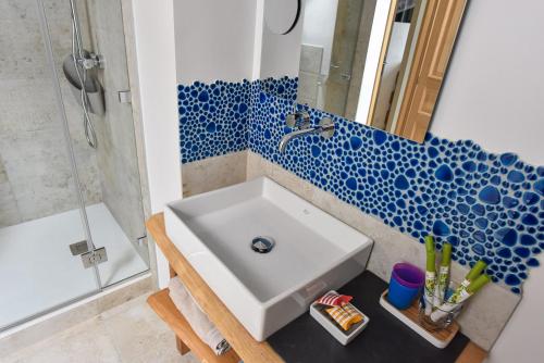 La salle de bains est pourvue d'un lavabo et d'un mur carrelé bleu et blanc. dans l'établissement Petite Emeraude, à Cancale