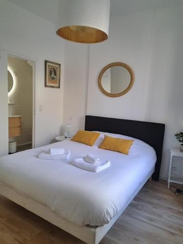 - une chambre avec un grand lit blanc et des oreillers jaunes dans l'établissement Agréable 2 pièces - rue du vieux Versailles, à Versailles