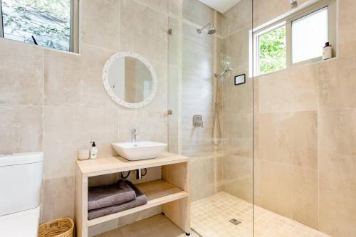 uma casa de banho com um lavatório e uma cabina de duche em vidro. em Orchard Lane na Cidade do Cabo