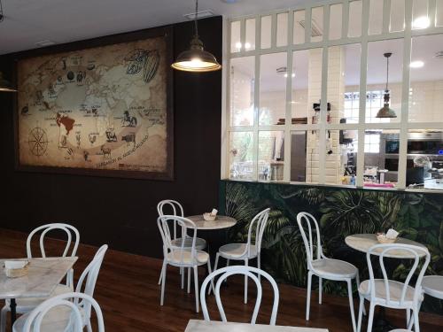 a restaurant with white chairs and tables and a painting on the wall at El Indio CHocolatería Boutique Hostel in Pinto