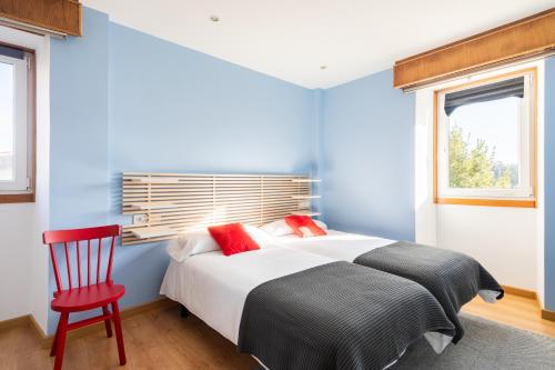 een blauwe slaapkamer met een bed en een rode stoel bij A casa de Valenza 