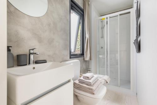 a white bathroom with a sink and a toilet at Al Lago Camping & Rooms in Riva del Garda