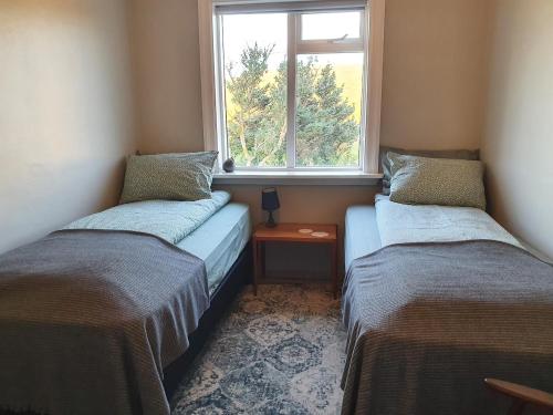 2 łóżka w małym pokoju z oknem w obiekcie Tjörn 1 w mieście Hvammstangi