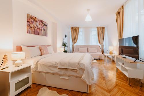 a white bedroom with a bed and a television at ALBERT RESIDENCE Aparthotel in Braşov