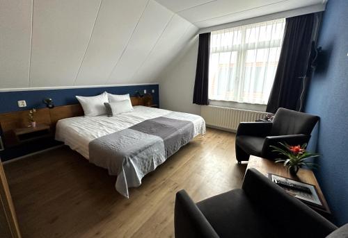 um quarto com uma cama e uma cadeira num quarto em DuinHotel Texel em De Koog
