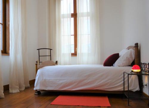 um quarto com uma cama com lençóis brancos e janelas em L'esprit d'antan, quartier historique deux personnes em Chartres