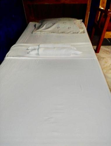 a bed with two white sheets on top of it at Fumiko Rina Acop in San Juan