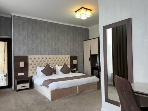 una camera con un grande letto e uno specchio di Hotel FN Shymkent a Shymkent