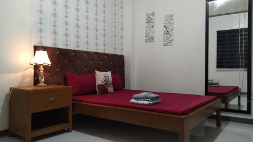 um quarto com uma cama com lençóis vermelhos e um candeeiro em ELEN INN - Malapascua Island - Private Fan room with shared bathroom #5 em Malapascua