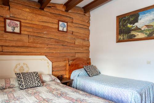 1 dormitorio con 2 camas y pared de madera en Masia Mas Bolet, en Palafolls