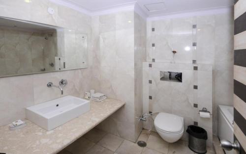 a white bathroom with a sink and a toilet at Shiva Oasis Resort in Neemrana