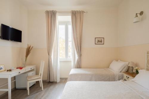 1 dormitorio con 2 camas, escritorio y ventana en Dante's in Vaticano 2 en Roma