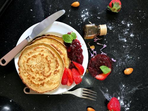 a plate of pancakes and strawberries on a table at Roomshala 152 Hotel Sukoon - Ramesh Nagar Metro Station in New Delhi