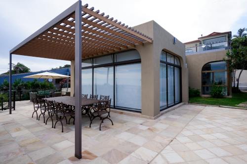 a patio with a table and chairs under a pergola at 145 Forest Drive - Umhlanga in Durban