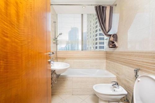 a bathroom with a tub and a toilet and a sink at Trident Grand Residence,Dubai Marina - 3BR Apartment - Allsopp&Allsopp in Dubai