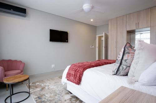 a bedroom with a white bed and a pink chair at 145 Forest Drive - Umhlanga in Durban