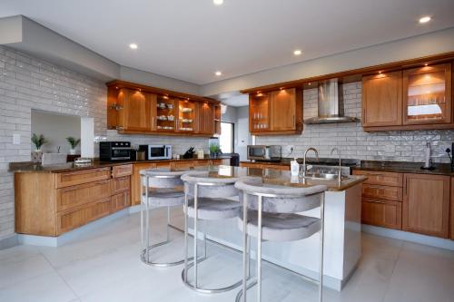 a large kitchen with wooden cabinets and bar stools at 145 Forest Drive - Umhlanga in Durban