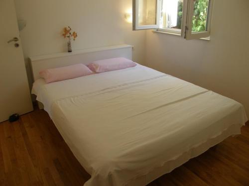 a white bed in a room with a cross on the wall at Apartments Boris in Omiš