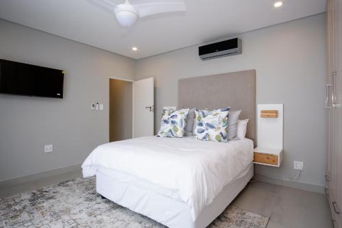 a bedroom with a white bed and a flat screen tv at 145 Forest Drive - Umhlanga in Durban