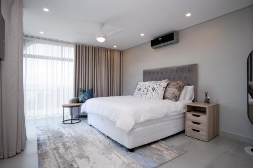 a bedroom with a white bed and a large window at 145 Forest Drive - Umhlanga in Durban