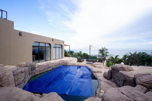 a swimming pool with rocks and a house at 145 Forest Drive - Umhlanga in Durban