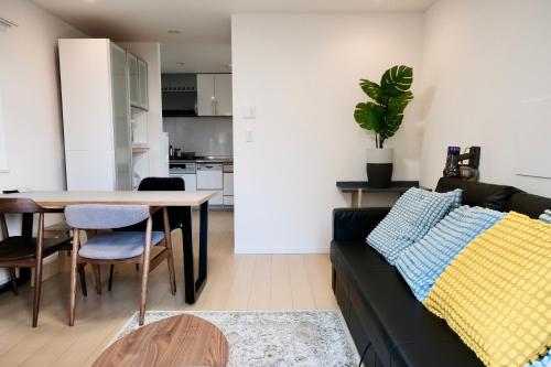 a living room with a black couch and a table at 100㎡ Cozy Villa in Shinjuku｜JR Shin-Ōkubo Sta. 7mins. in Tokyo