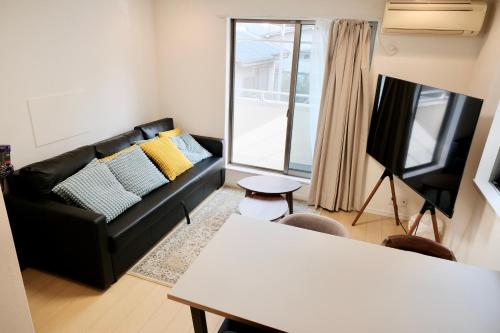 a living room with a black couch and a table at 100㎡ Cozy Villa in Shinjuku｜JR Shin-Ōkubo Sta. 7mins. in Tokyo