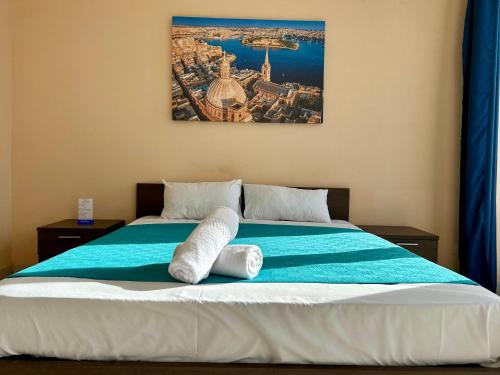 Una cama con dos toallas blancas encima. en Malta Paradise Central Hotel, en San Julián