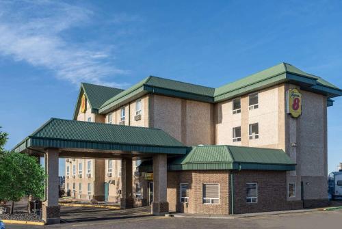 a large brick building with a green roof at Super 8 by Wyndham Edmonton International Airport in Leduc