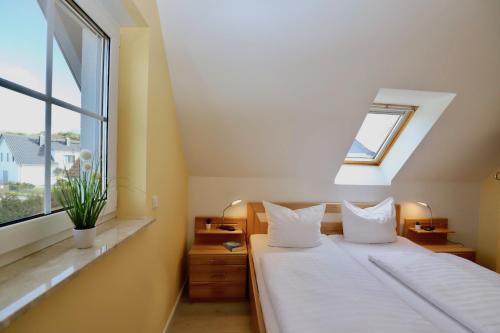 a bedroom with a white bed with a window at Haus Sonne Ferienwohnung 5 in Thiessow