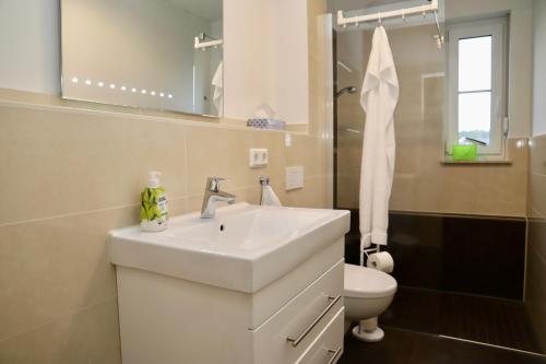 a bathroom with a white sink and a toilet at Haus Sonne Ferienwohnung 5 in Thiessow